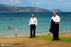 Le joueur de viole Derek Hensle, le chef d’orchestre Milen Nachev et une mouette néo-zélandaise bravent les vents forts qui balayent la baie de Port Fitzroy. (Photo par le danseur Ben Chen)