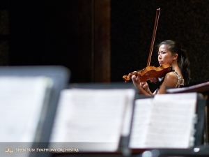 Déjà changée pour la performance, la violoniste Fiona Zheng profite d’une dernière opportunité pour pratiquer sur scène.