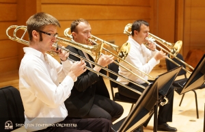 La section de trombones s’entraîne ensemble avant la répétition. La section comprend (de gauche à droite) Alistair Crawford (premier tromboniste), Ivan Agarkov et Pavlo Baishev (tromboniste basse).