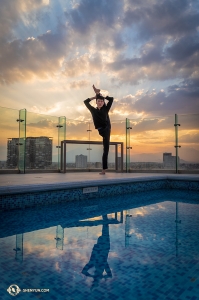 <p>Depuis le toit de l'h&ocirc;tel, le danseur Edwin Fu se tient en &eacute;quilibre sur une jambe pr&egrave;s de la piscine. (Photo de William Li)&nbsp;</p>